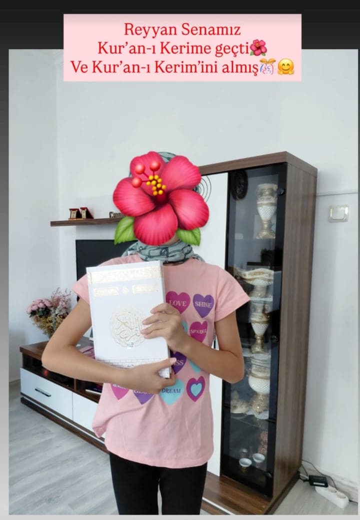 Yüzü çiçekle kapatılmış kız öğrenci elinde yeni Kur'an-ı Kerim'iyle